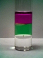 sample vial containing 3-phases, consisting of an organic layer (pink), water layer (green) and an asymmetric quaternary ammonium ionic liquid (clear) layer